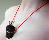 Alchemy life-form on silver and red rubber tubing necklace attachment.